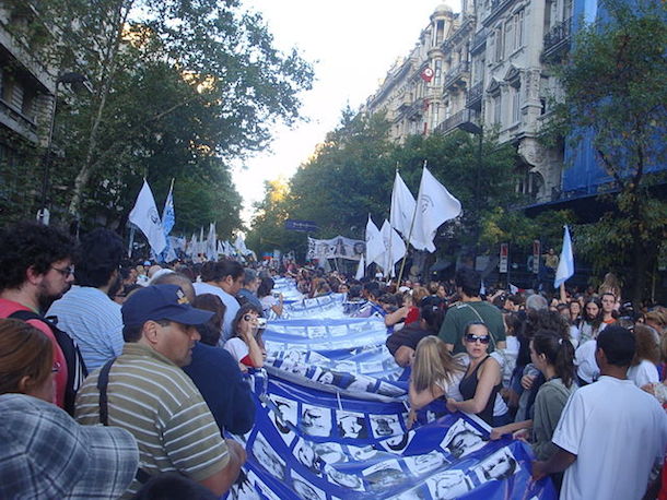 Argentineans carrying a flag with the pictures of people who went missing during the military dictatorship